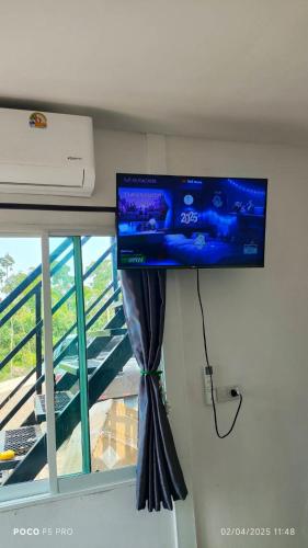 a flat screen tv hanging on a wall next to a window at ภูโอบตะวันรีสอร์ต - Phu Oab Tawan Resort in Nan