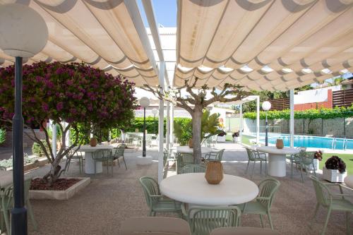 a patio with tables and chairs under an umbrella at Casual Bahía Ibiza in San Antonio Bay