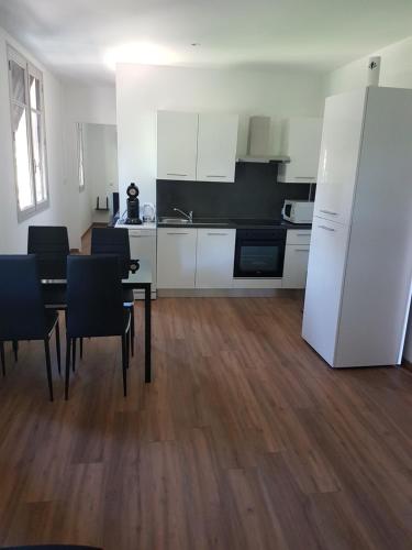 une cuisine avec une table et des chaises et un réfrigérateur blanc dans l'établissement First, à Saint-Hilaire-de-Brethmas