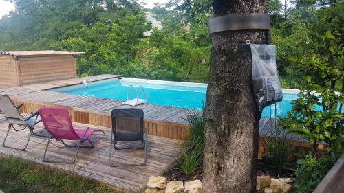 une piscine avec deux chaises et un arbre dans l'établissement First, à Saint-Hilaire-de-Brethmas