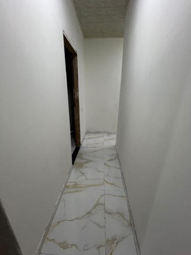 an empty corridor with white walls and marble floors at Eri House Home in Ananindeua