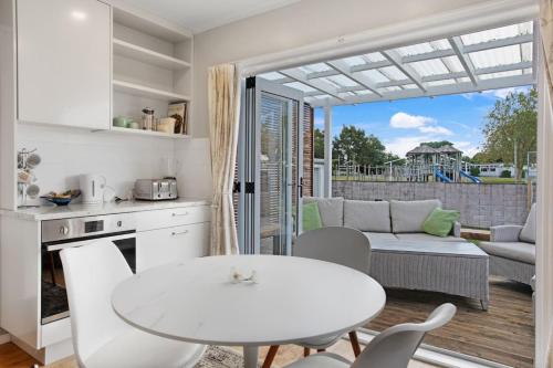 eine Küche und ein Wohnzimmer mit einem weißen Tisch und Stühlen in der Unterkunft Spacious Papakura Family Delight w Deck and Yard in Papakura