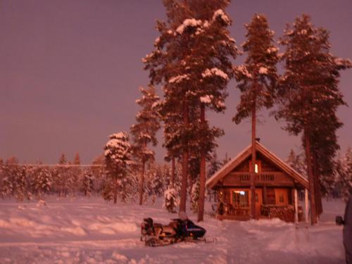 une cabane en rondins dans la neige avec des arbres dans l'établissement Ranta Äärelä, à Vuotso
