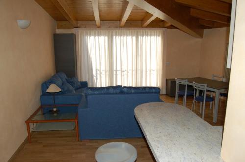 a living room with a blue couch and a table at Hotel Concordia in Porlezza