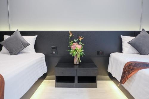 a room with two beds and a vase with flowers on a table at Lorjula INN in Hat Yai