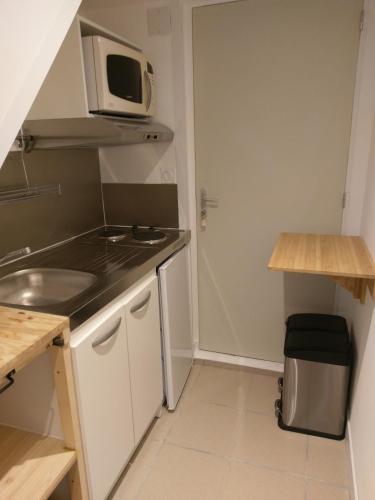 une petite cuisine avec un micro-ondes et un évier dans l'établissement Cholet Camp de base pour visiter la Région 25 minPuyduFou, parcoriental, châteaux de la Loire, Nantes, à Cholet
