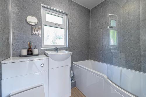 a bathroom with a sink and a tub and a mirror at Finest Retreats - Lindisview in Caernarfon