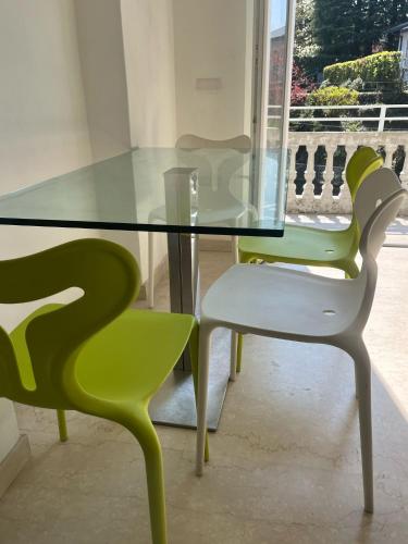 a glass table and two green chairs in a room at Red Leaf in Como