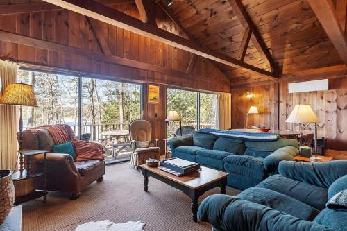 a living room with blue couches and a table at Lakeside Getaway - Lake Access & Firepit in Wolfeboro