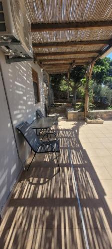 a patio with a table and a bench under awning at Anemos in Tsoútsouros
