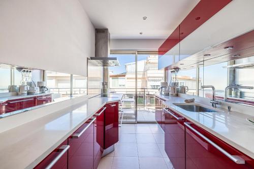 une grande cuisine avec des comptoirs blancs et des armoires rouges dans l'établissement Latour Maubourg 20 by Halldis, à Cannes