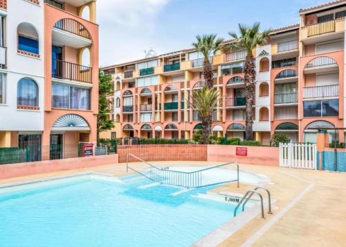 - une piscine en face d'un immeuble dans l'établissement Appartement avec piscine proche ile des loisirs, au Cap d'Agde