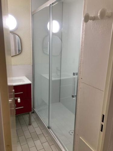 une douche avec une porte vitrée dans une salle de bain dans l'établissement Appartement avec piscine proche ile des loisirs, au Cap d'Agde