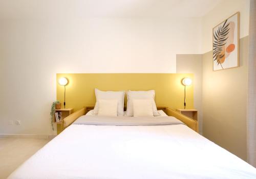 une chambre avec un grand lit blanc avec deux lampes dans l'établissement Studio rénové, 5mn plage, terrasse, clim, vélos, à Saint-Mandrier-sur-Mer