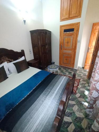 a bedroom with a bed and a wooden door at Riad lala Drissia in Gare de Tanger-Fès