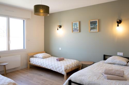 a bedroom with two beds and a window at gite des coulées nantaises in Le Cellier