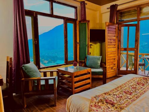 a bedroom with a bed and a table and windows at Naina Spring Resort, Manali - away from city hustle in Manāli
