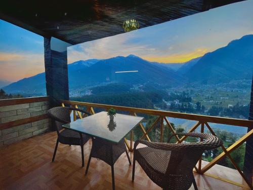 a table and chairs on a balcony with a view at Naina Spring Resort, Manali - away from city hustle in Manāli