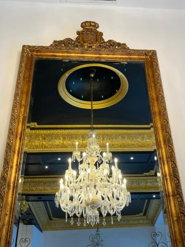 a gold mirror with a chandelier hanging from it at Adriano Boutique Sevilla in Seville