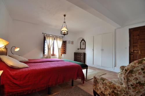 a bedroom with a red bed and a chair at Casa Rural Finca Buenavista in Valdeganga de Cuenca