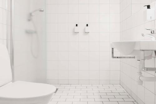 a white bathroom with a toilet and a sink at Scandic Västerås in Västerås