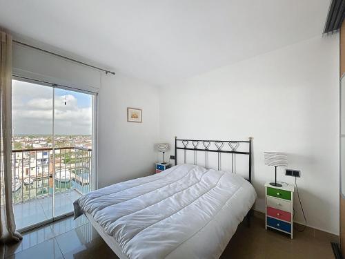 a white bedroom with a bed and a large window at Port Grec 3 - Piso vista al puerto y montana in Empuriabrava
