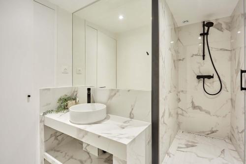 une salle de bain blanche avec un lavabo et une douche dans l'établissement Apartment Pantheon Nôtre Dame by Studio prestige, à Paris