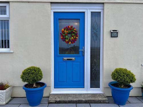 a blue front door with a wreath on it at Chic Retreat Apartment Sleeping Two in Loughor