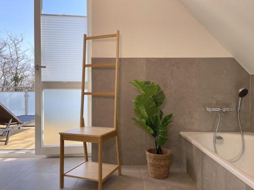 Un baño con bañera, una silla y una planta. en Am Dahmer Leuchtturm 23d, en Dahme