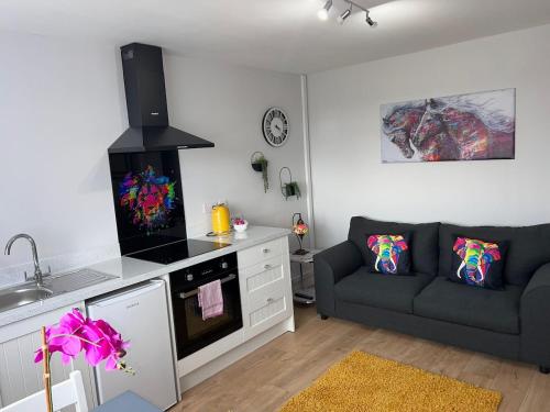 a living room with a couch and a kitchen at Chic Retreat Apartment Sleeping Two in Loughor