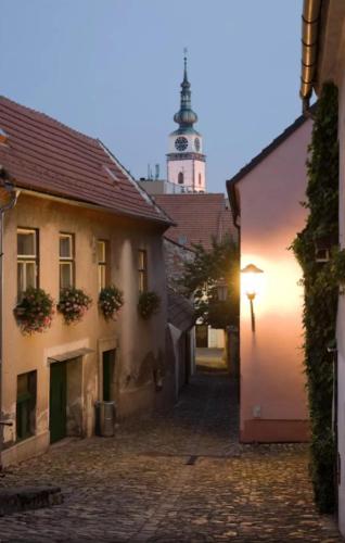an alley with a building with a clock tower in the background at Apartmá Na palírně in Třebíč