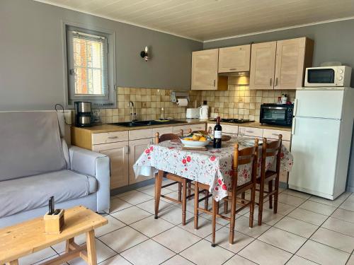 une cuisine avec une table, des chaises et un réfrigérateur dans l'établissement Gîte - Plein sud, à Mieussy