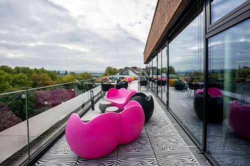 a group of pink chairs sitting on a balcony at Prize by Radisson, Bonn City in Bonn