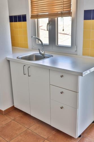 a white kitchen with a sink and a window at Apartamentos Arnela in Camariñas