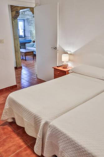 a bedroom with a white bed with a lamp on a table at Apartamentos Arnela in Camariñas