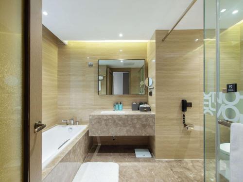 a bathroom with a tub and a sink at Novotel Wuxi in Wuxi