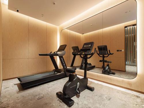 a gym with tread machines and a mirror at Novotel Wuxi in Wuxi