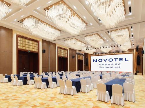 a large banquet hall with white chairs and a stage at Novotel Wuxi in Wuxi