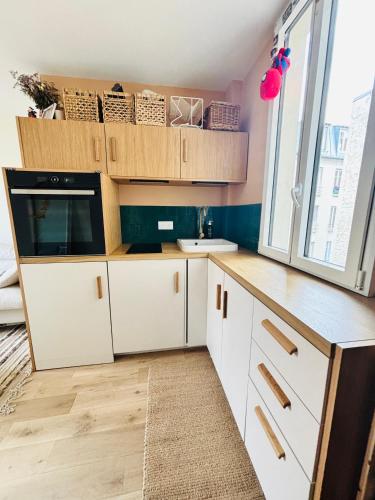 une cuisine avec des armoires blanches et un évier dans l'établissement Studio Sorbonne, à Paris