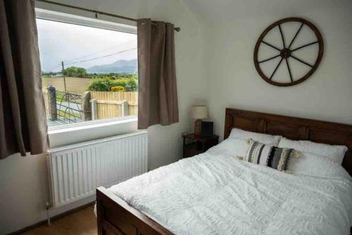 ein Schlafzimmer mit einem Bett und einem großen Fenster in der Unterkunft Roddys cottage three bedroom with hot tub sleeps6 in Magherasaul