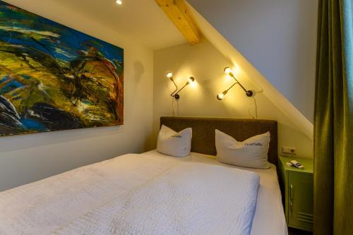 a bedroom with a white bed with a painting on the wall at Hotel-Restaurant Kostbar in Engen