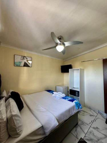 a bedroom with a bed with a ceiling fan at Kitty Guest House in Bellville