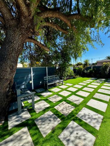 a picnic table and a bench under a tree at Kitty Guest House in Bellville