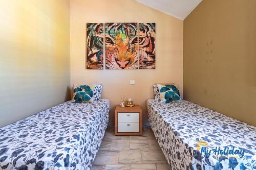 ein Schlafzimmer mit zwei Betten und einem Gemälde an der Wand in der Unterkunft Casa Noray del Mar in Castillo del Romeral