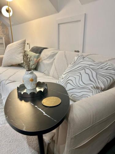 a table with a vase on it next to a couch at Cosy Hideaway Studio in Walsall in Pelsall