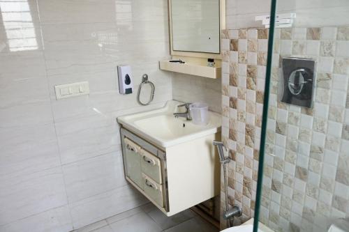 a white bathroom with a sink and a shower at Vinayak Stay Sector 43 in Gurgaon