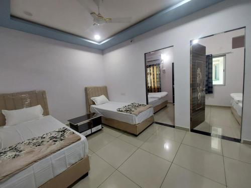 a hotel room with two beds and a mirror at Madhavrai rooms in Kevadia