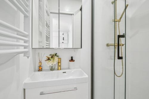 une salle de bain blanche avec un lavabo et un miroir dans l'établissement 9 min de la Basilique Saint-Denis - 10 voyageurs, à Saint-Denis