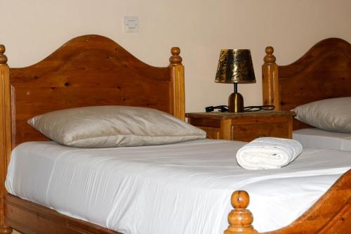 a bedroom with two beds with white sheets and a lamp at Auberge Les Montagnes du Paradis Your Hidden Retreat in Paradise Valley in Agadir