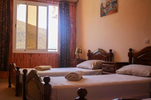 two beds in a room with a window at Auberge Les Montagnes du Paradis Your Hidden Retreat in Paradise Valley in Agadir